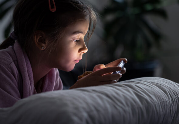 Menina usa celular em casa